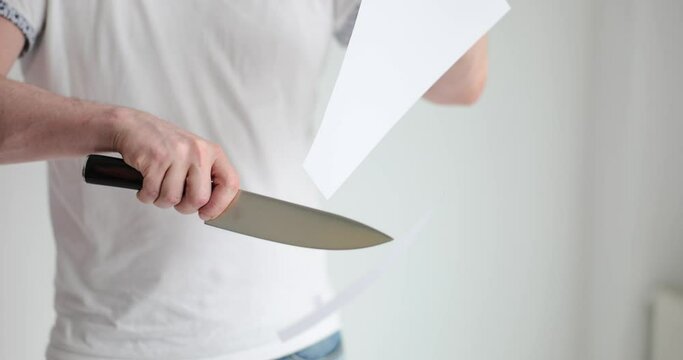 Man demonstrates the sharpness of knife cutting thin sheet of paper. Razor sharp blade
