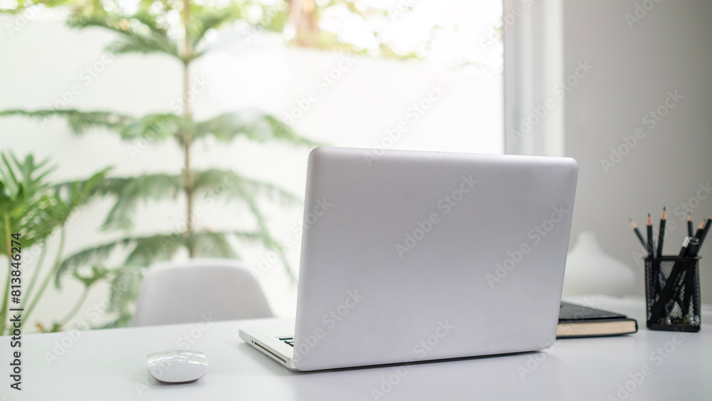 Poster laptop computer on white table near window with view of garden.