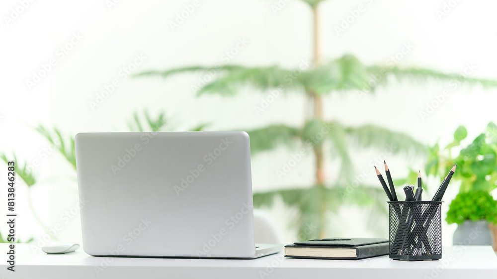 Poster laptop computer on white table near window with view of garden.