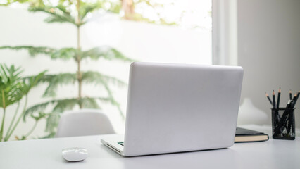 Laptop computer on white table near window with view of garden.