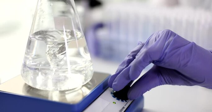 Chemical laboratory glass flask with clear liquid is mixed with magnetic stirrer. Investigation of properties and quality of water