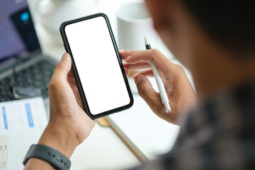 Young man holding mockup smart phone with white empty screen. Close up view.