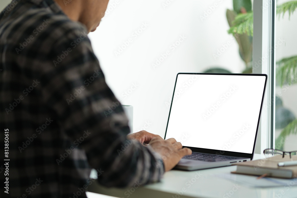 Poster view over shoulder businessman using laptop computer on table at home office..