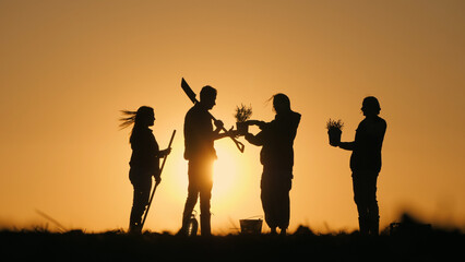 A group of farmers chatting in a field at sunset. With them their work equipment and seedlings