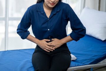 A woman is sitting on a bed with a blue sheet