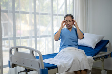 A woman in a blue hospital gown is sitting on a hospital bed