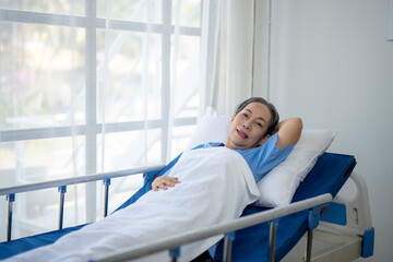 A woman is laying in a hospital bed with a blue sheet