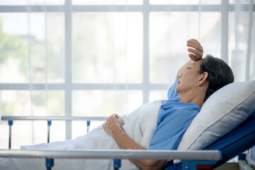 A woman in a hospital bed is sweating and holding her head