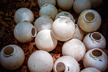 Pile of old white lanterns discarded in garden. Old street lights have been damaged piled together....