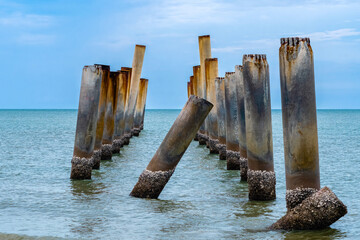 Beautiful view of leaning pillars of the old pier. Slanted concrete pole beach. Abandoned fishing...