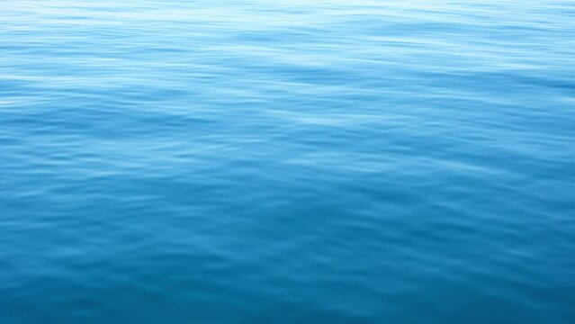 Continuously changing deep blue sea or ocean surface for a background. Beautiful fresh wavy water on a cloudy afternoon. Calm and meditative nature concept. Abstract minimalistic slow motion.