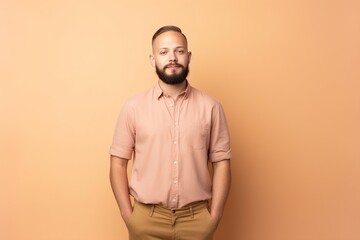 Fototapeta premium A man with a beard and a pink shirt is standing in front of a yellow wall