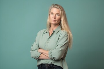 A woman with long blonde hair is standing in front of a blue wall