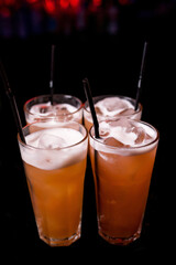 Four yellow cocktails with ice in glasses. Mixing an alcoholic cocktail in a nightclub, pub, restaurant