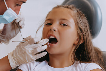 A cheerful girl undergoes a dental examination in a modern pediatric dentistry clinic