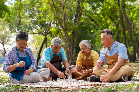 A group of Asian senior people enjoy painting cactus pots and recreational activity or therapy outdoors together  at an elderly healthcare center, Lifestyle concepts about seniority - Powered by Adobe