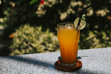 Freshly squeezed citrus juice on the table in the sun. Delicious orange and tangerine juice on a tropical background