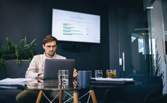 Business man using a laptop, preparing to give a report on his market research before a conference meeting