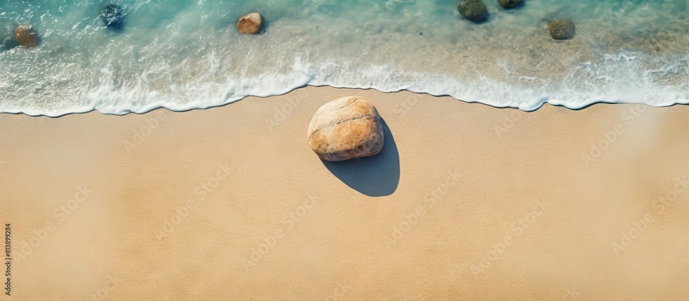 Poster top view of a stone resting on the sandy beach creating a serene summer beach background with ample 