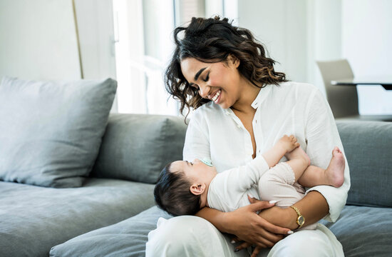 Beautiful young black mother hugging children at home - Happy mom sitting on sofa with her daughter - Parent, family and new born life style concept
