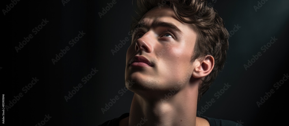 Poster a pensive young man with a casual demeanor gazes upward in a close up portrait leaving adequate empt