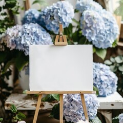 An easel stands with a blank canvas propped up in front of a cluster of vibrant blue hydrangea flowers. horizontal banner, copy space