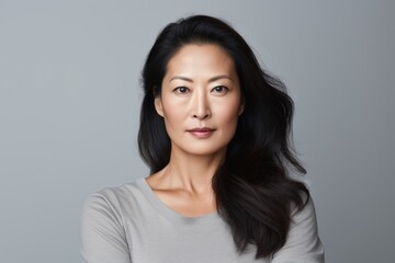 Portrait of a tender asian woman in her 40s with arms crossed isolated in white background
