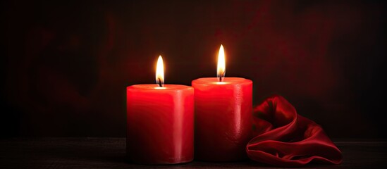 Dark background with two red burning candles providing ample copy space image