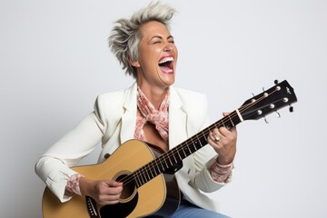 Obraz premium Portrait of a joyful woman in her 40s playing the guitar while standing against white background