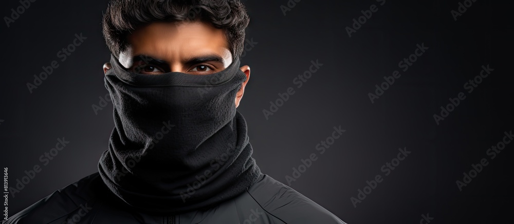 Poster a middle eastern man is pictured on an isolated background wearing a gray turtleneck and a black fac