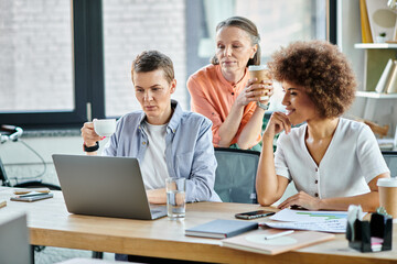 Diverse group of hardworking businesswomen at a table with a laptop in a coworking space.