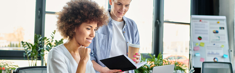 Diverse women analyze data on a computer screen in an office setting.