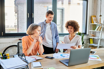 Fototapeta premium Hardworking businesswomen, diverse and inclusive, gather around a wooden table in an office setting to work together.