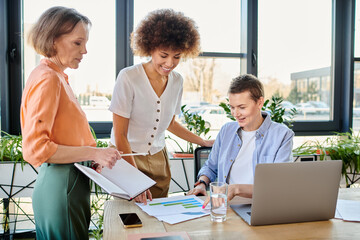 Diverse group of businesswomen engage with a laptop in a modern office setting.