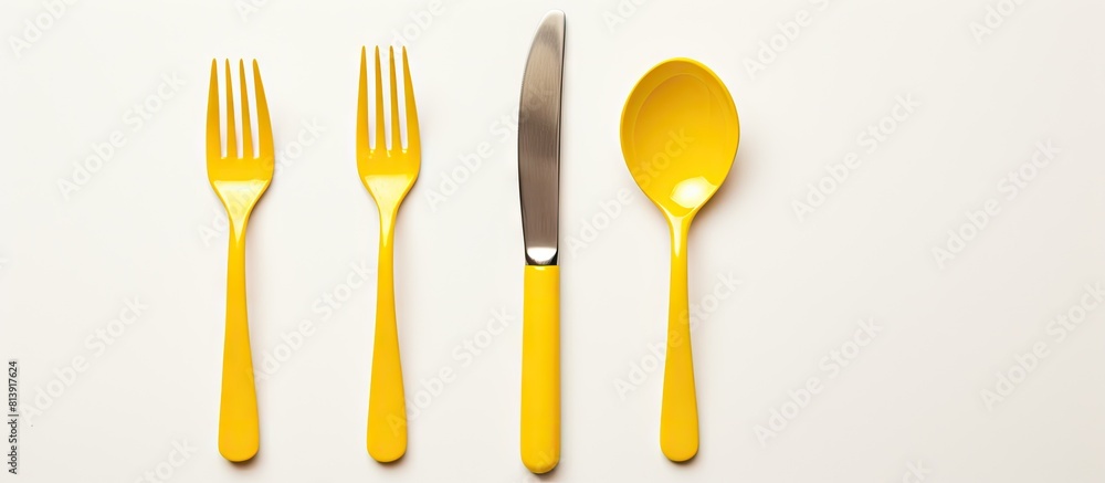 Poster a top down view of a white background with a yellow fork knife and spoon arranged neatly there is am