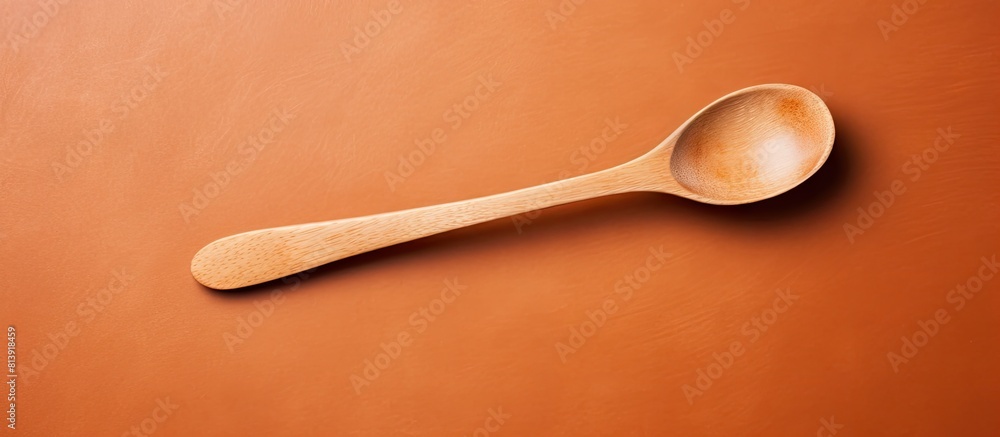Poster a wooden spoon rests on a brown background creating a copy space image