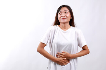 Asian Woman having stomach ache, bending and holding hands on belly, discomfort from menstrual...