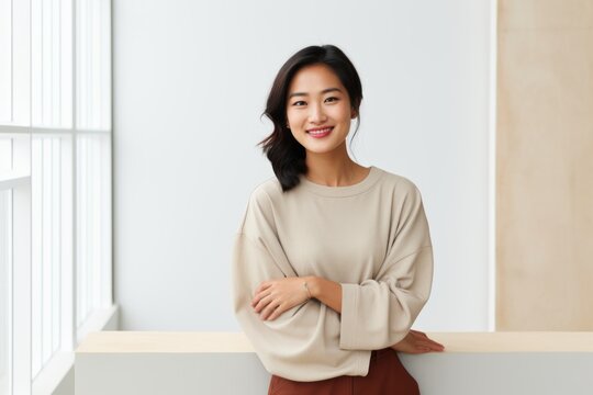 Portrait of a satisfied asian woman in her 30s showing a thumb up isolated in modern minimalist interior