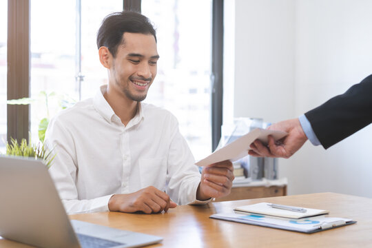 Good job Asian manager business man giving financial reward in an envelope, business letter extra salary to company employee, male worker office hand received premium bonus, getting cheque from boss.