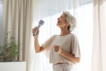Portrait of a jovial woman in her 50s dancing and singing song in microphone in modern minimalist...