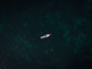 Bateau de pêcheur rouge et blanc seul au milieu de l'océan, perdu au milieu de la mer. 