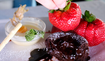  Chocolate fondant with strawberries and spoon on plate, isolated on white background, top view