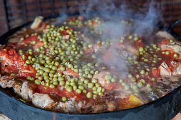 Close-up Pollo al disco cooking with tomato sauce and peas. Typical Argentinean gastronomy
