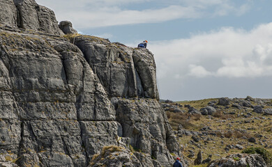 Climber wearing a red helmet sat on the edge of a rock