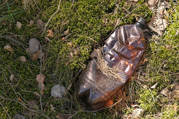 Closeup of an empty plastic bottle lying on the ground in nature, pollution of nature