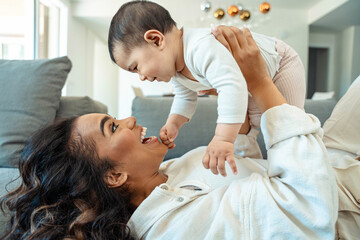 Happy black mother playing with daughter lying on sofa - Delightful mom relaxing with baby indoors...