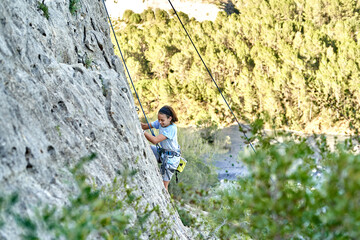 A young boy practices climbing skills on a rock wall in the mountains