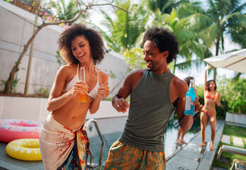 People having fun in a tropical pool house. Man and woman dancing, smiling, having fun.