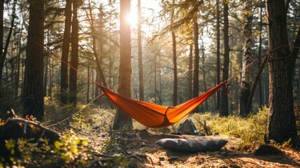 A hammock hangs between trees in a forest, with a sleeping bag inside.