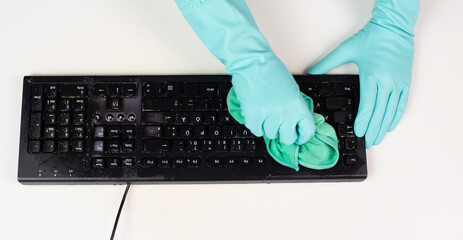 Cleaning computer keyboard in office with a wet wipe rag, dusty and dirty electronic, housework 